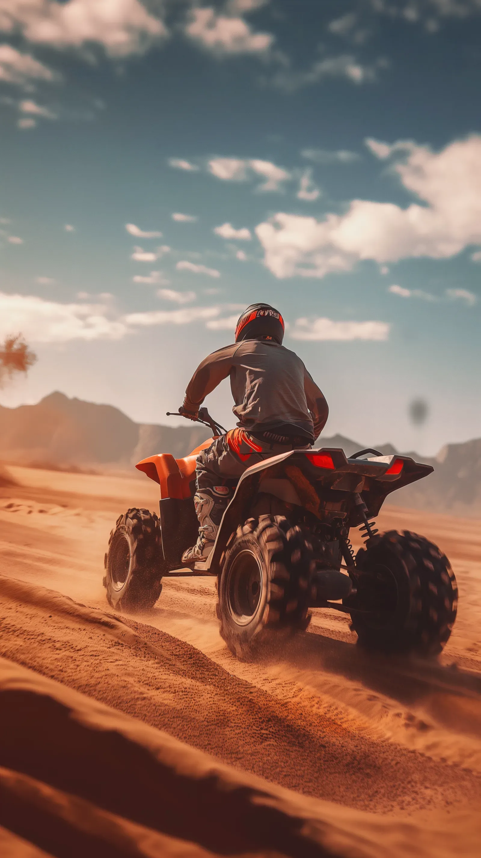 Helmeted rider on an orange quad in the dunes, from the QuadParts website